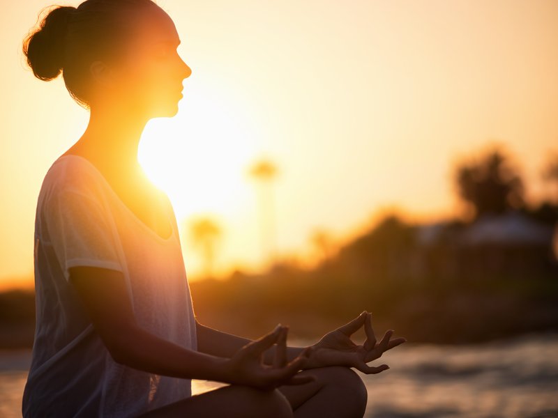 Femme en méditation lotus au coucher du soleil cultivant sa dimension spirituelle