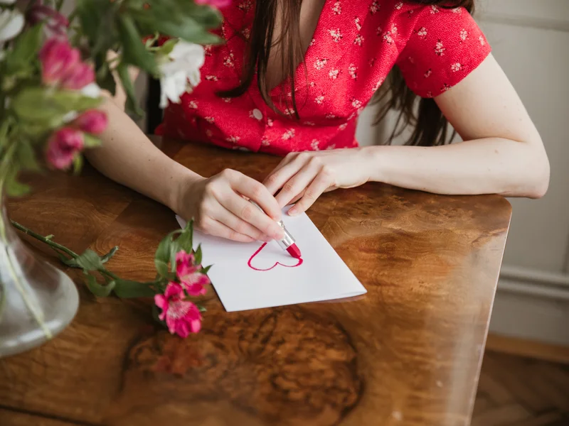 Main écrivant une lettre d’amour sur un carnet, plume au-dessus du papier, lumière naturelle