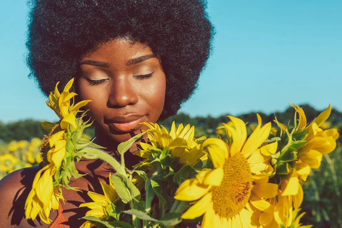 Femme noire dans un champs de tournesol dans son énergie féminine